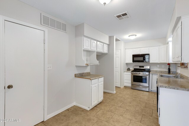 kitchen featuring white cabinets, sink, and stainless steel range with gas stovetop