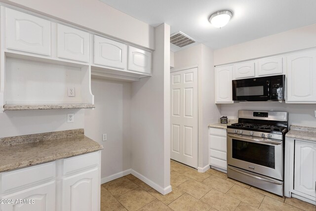 kitchen with stainless steel gas stove, white cabinetry, and light tile patterned flooring