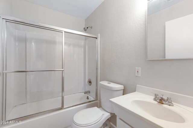 full bathroom featuring enclosed tub / shower combo, lofted ceiling, vanity, and toilet