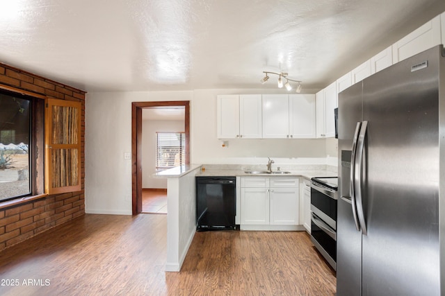 kitchen featuring a sink, wood finished floors, light countertops, white cabinets, and appliances with stainless steel finishes