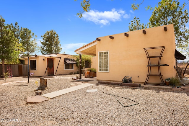 back of house featuring stucco siding and fence