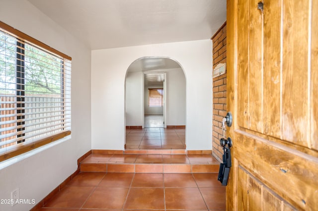 interior space with tile patterned flooring, a wealth of natural light, arched walkways, and baseboards