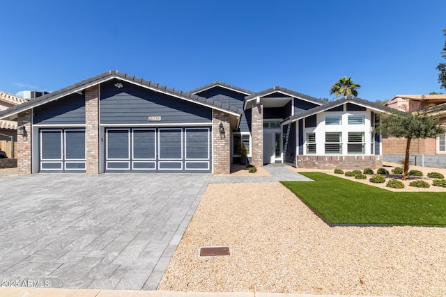 view of front of property featuring a tiled roof, an attached garage, brick siding, and driveway