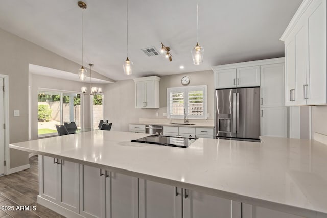 kitchen with a sink, white cabinetry, stainless steel appliances, dark wood-style flooring, and vaulted ceiling