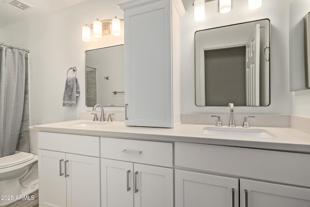 bathroom with double vanity, visible vents, toilet, and a sink