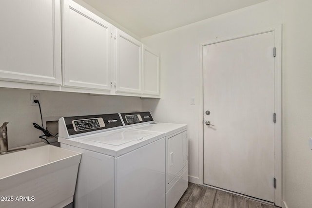 washroom featuring separate washer and dryer, wood finished floors, cabinet space, and a sink