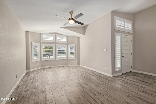 interior space with a ceiling fan, lofted ceiling, baseboards, and wood finished floors