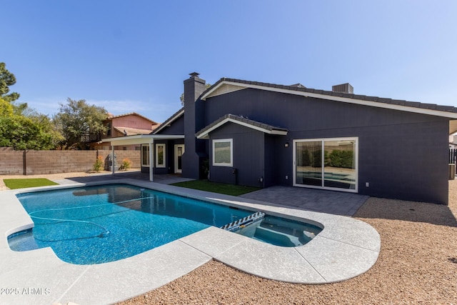 view of pool featuring a pool with connected hot tub, a patio area, and a fenced backyard