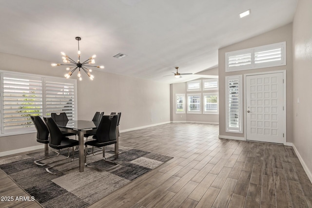 dining room with visible vents, baseboards, vaulted ceiling, ceiling fan with notable chandelier, and wood finished floors