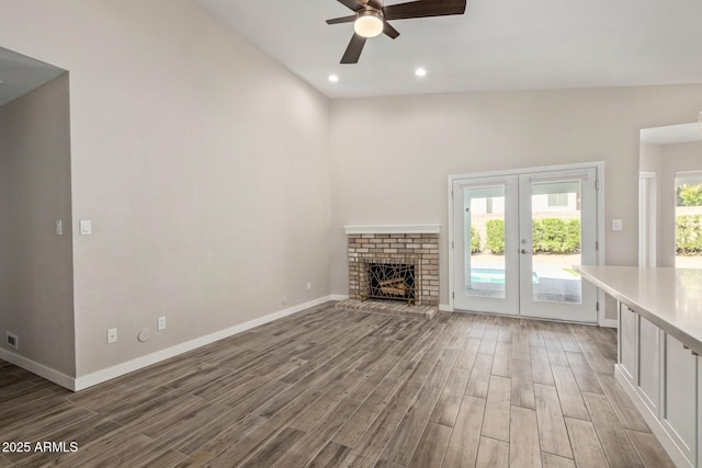 unfurnished living room with wood finished floors, recessed lighting, french doors, baseboards, and a brick fireplace