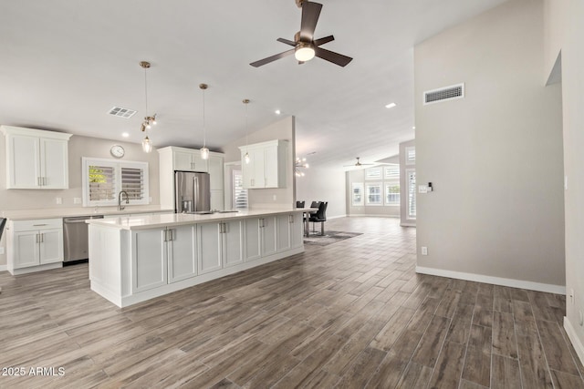 kitchen featuring light wood-style flooring, open floor plan, appliances with stainless steel finishes, white cabinets, and light countertops