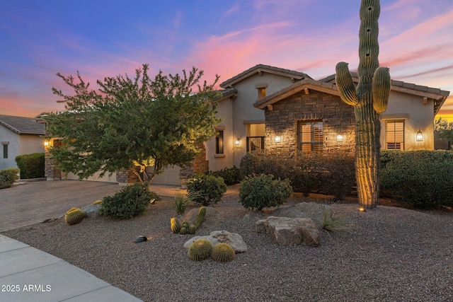 view of front of house featuring stucco siding, driveway, and stone siding
