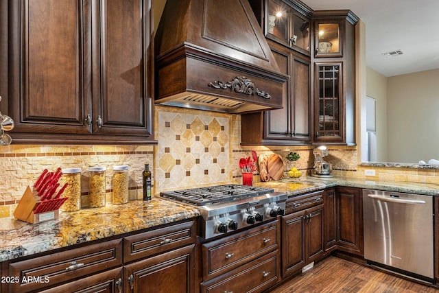 kitchen featuring custom exhaust hood, dark brown cabinetry, appliances with stainless steel finishes, and dark wood-type flooring