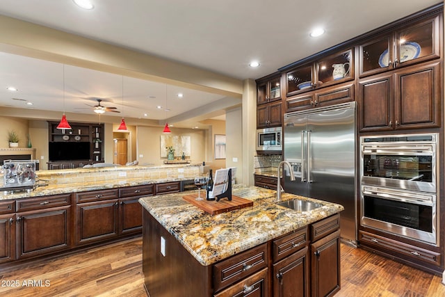 kitchen featuring built in appliances, tasteful backsplash, dark wood-type flooring, and hanging light fixtures