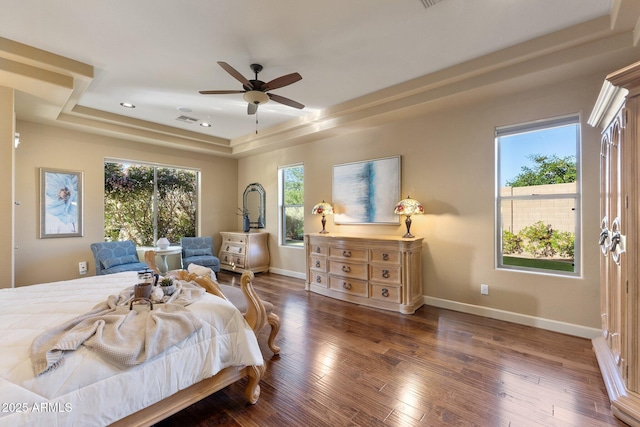 bedroom with a raised ceiling, visible vents, baseboards, recessed lighting, and wood finished floors