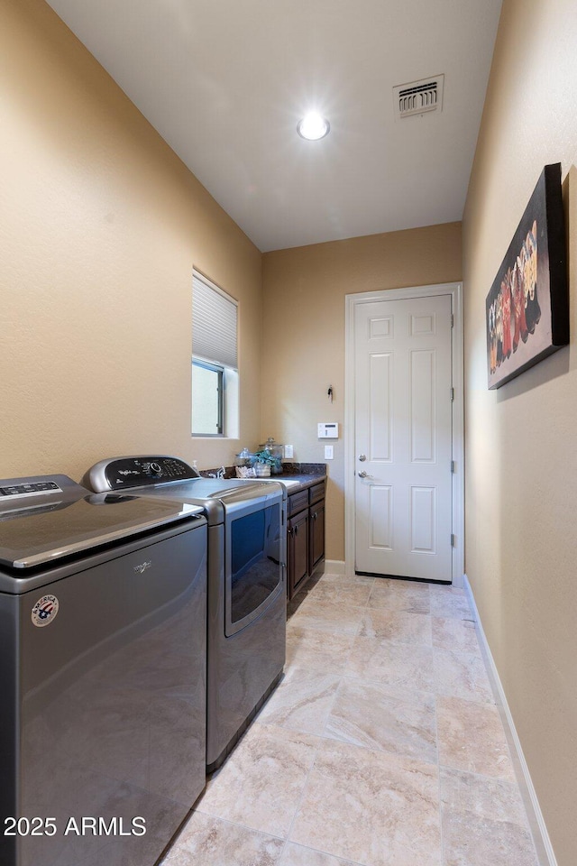 laundry room with visible vents, separate washer and dryer, cabinet space, and baseboards