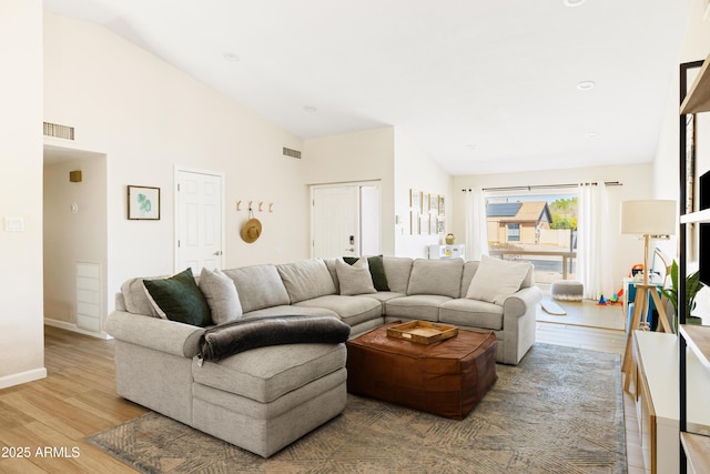 living room with light wood-type flooring, high vaulted ceiling, baseboards, and visible vents