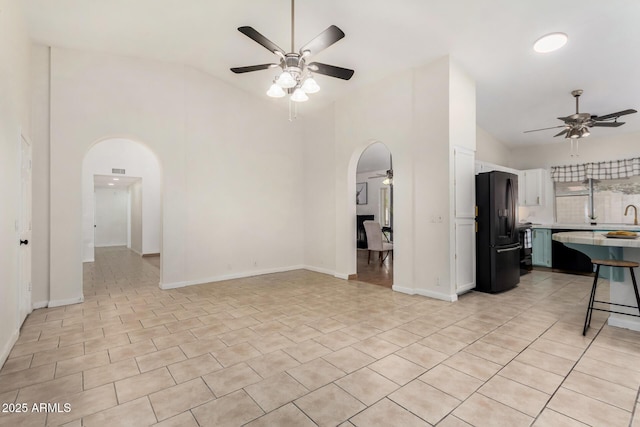 living room with arched walkways, light tile patterned floors, high vaulted ceiling, and a ceiling fan