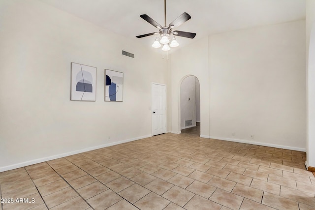 empty room featuring arched walkways, visible vents, a high ceiling, and ceiling fan