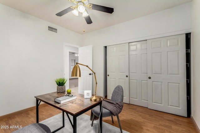 home office with a ceiling fan, visible vents, light wood finished floors, and baseboards