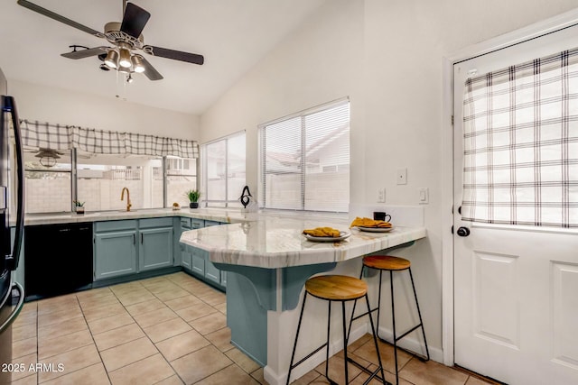 kitchen featuring a ceiling fan, a peninsula, light countertops, vaulted ceiling, and a kitchen breakfast bar