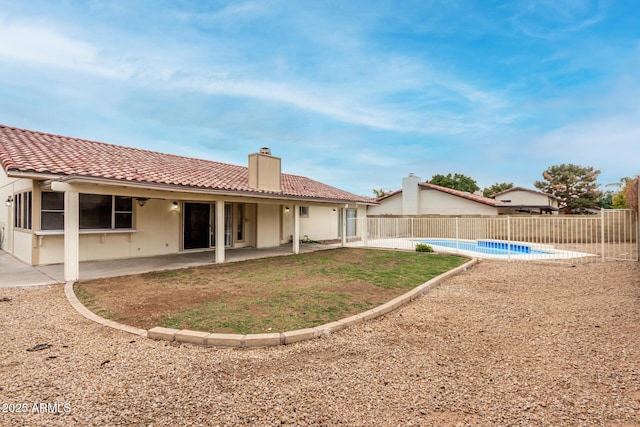 back of house featuring a fenced in pool, fence, a tile roof, a chimney, and a patio area