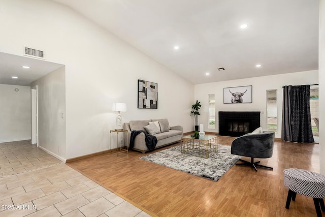 living room with visible vents, high vaulted ceiling, wood finished floors, and a fireplace