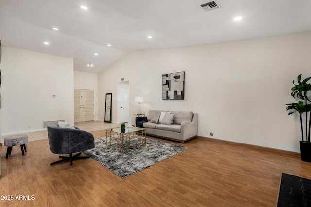 living area with visible vents, baseboards, light wood-style flooring, and vaulted ceiling