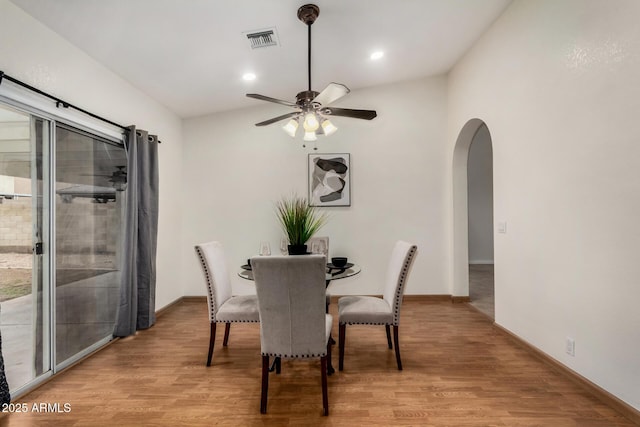 dining area with light wood-style flooring, arched walkways, visible vents, and ceiling fan