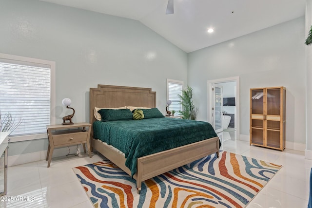 bedroom with vaulted ceiling, ceiling fan, light tile patterned floors, and ensuite bath