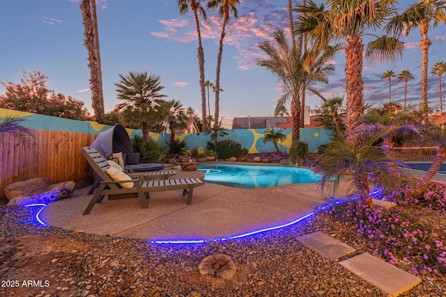 pool at dusk with a patio area