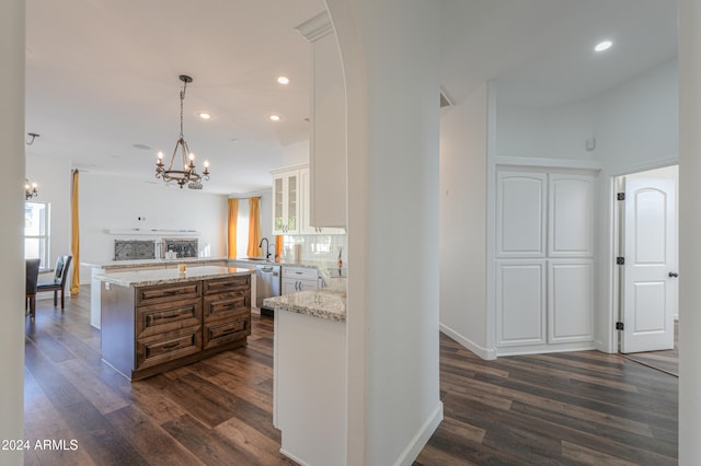 kitchen with dishwasher, kitchen peninsula, light stone countertops, white cabinets, and dark hardwood / wood-style flooring