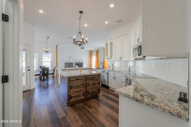 kitchen with kitchen peninsula, hanging light fixtures, white cabinetry, dark hardwood / wood-style floors, and stainless steel appliances