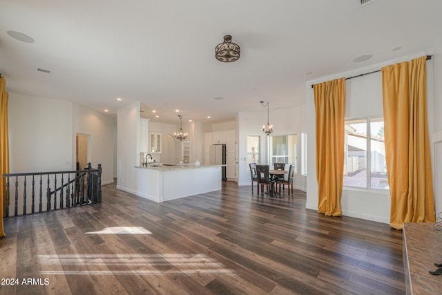 unfurnished living room with a notable chandelier, sink, and dark hardwood / wood-style floors