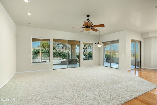 empty room with ceiling fan, a wealth of natural light, and light wood-type flooring