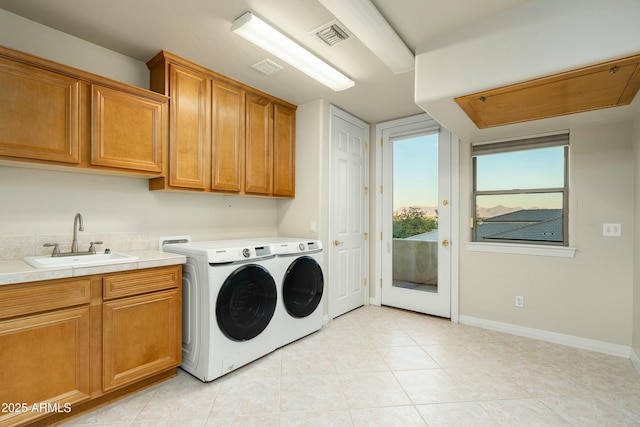 washroom featuring washing machine and dryer, light tile patterned flooring, sink, and cabinets