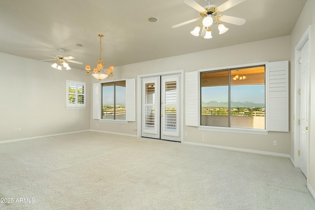 empty room with light carpet and ceiling fan with notable chandelier