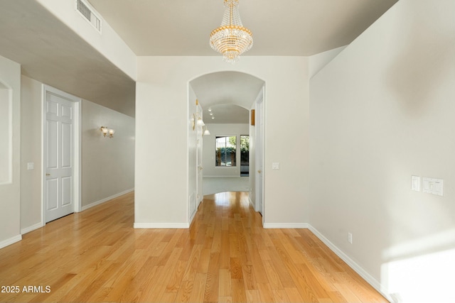 hallway with light hardwood / wood-style flooring and a chandelier