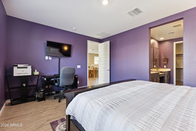 bedroom featuring connected bathroom and light hardwood / wood-style flooring