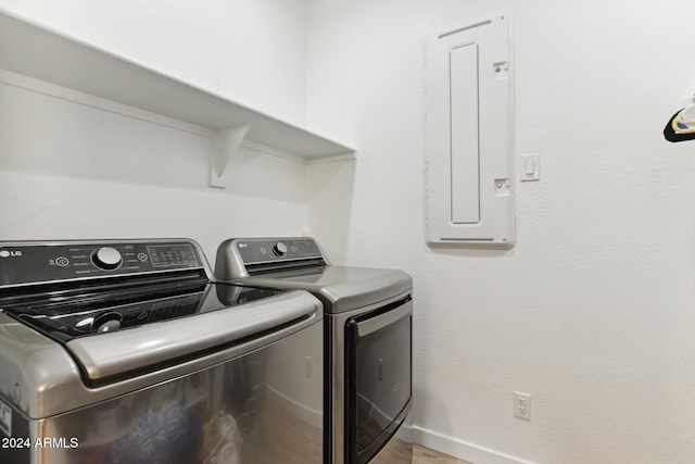 laundry area with electric panel, washer and clothes dryer, and light hardwood / wood-style floors