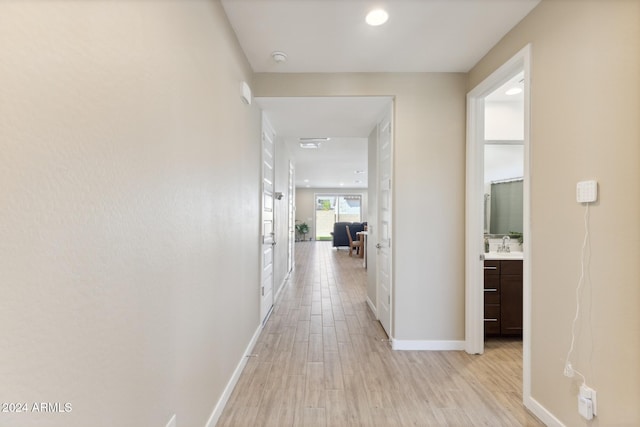 corridor with sink and light wood-type flooring