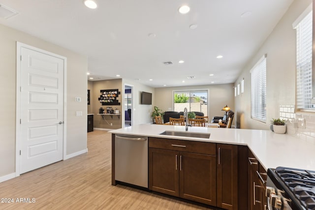 kitchen featuring kitchen peninsula, backsplash, sink, appliances with stainless steel finishes, and light hardwood / wood-style floors