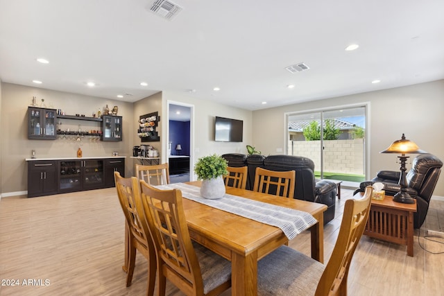 dining area featuring bar and light wood-type flooring