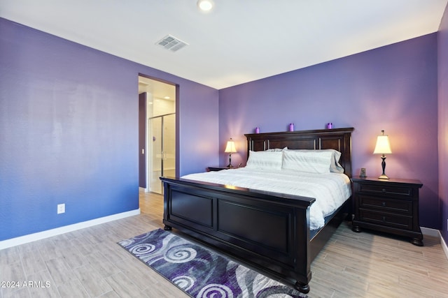 bedroom featuring connected bathroom and light wood-type flooring