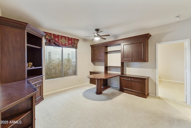 carpeted office space with ceiling fan and built in desk