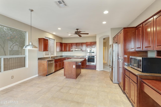 kitchen with ceiling fan, sink, a center island, decorative light fixtures, and appliances with stainless steel finishes