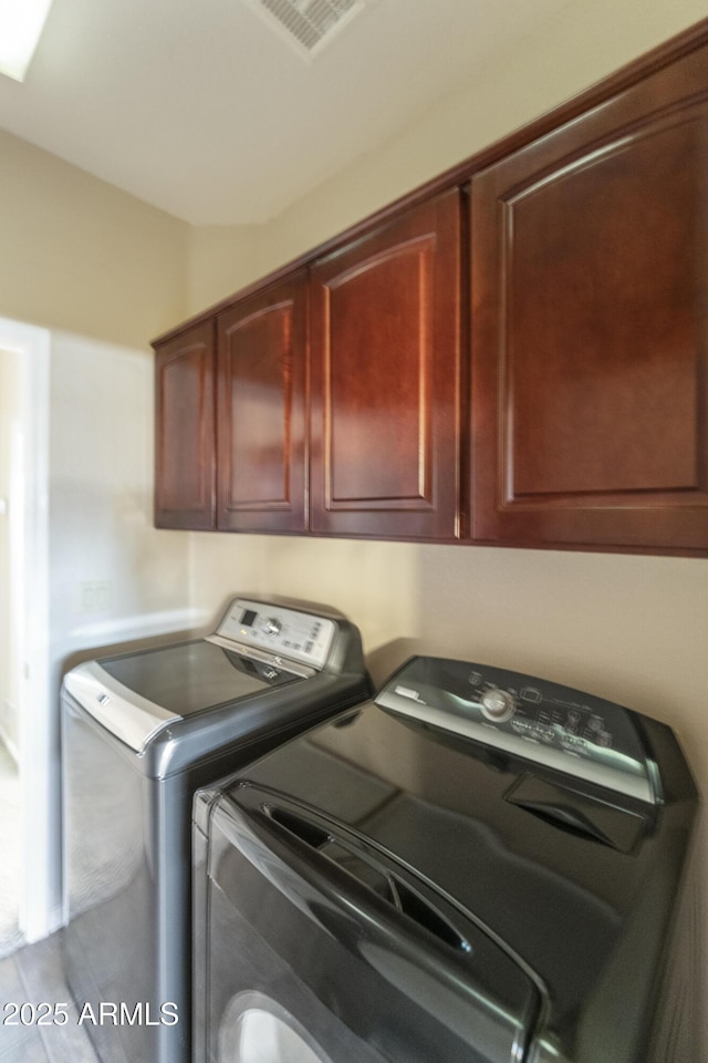 laundry room featuring washer and dryer and cabinets