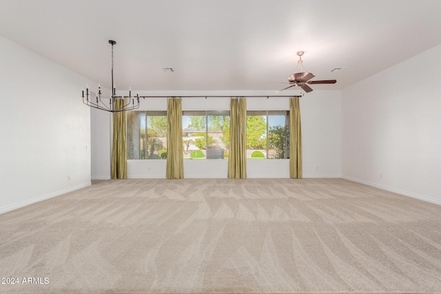 empty room with ceiling fan with notable chandelier and light colored carpet