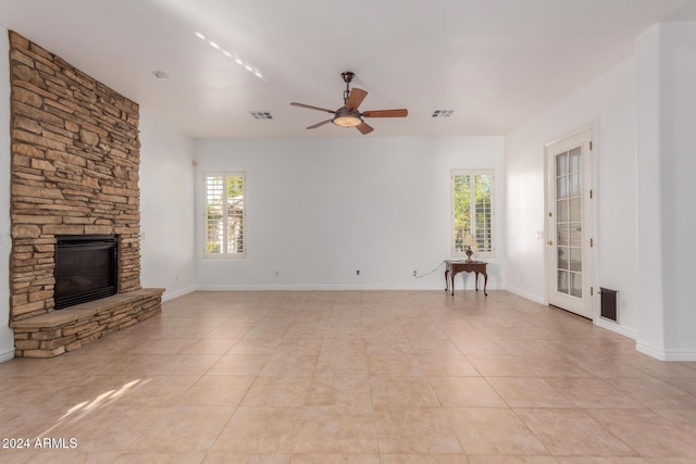 unfurnished living room featuring a fireplace, ceiling fan, plenty of natural light, and light tile patterned flooring