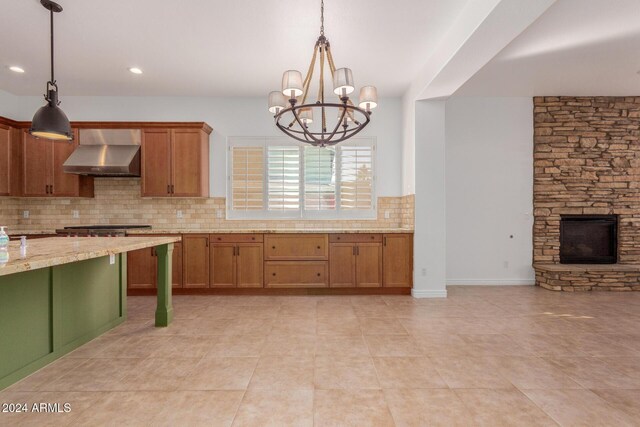 kitchen featuring wall chimney exhaust hood, decorative light fixtures, and decorative backsplash